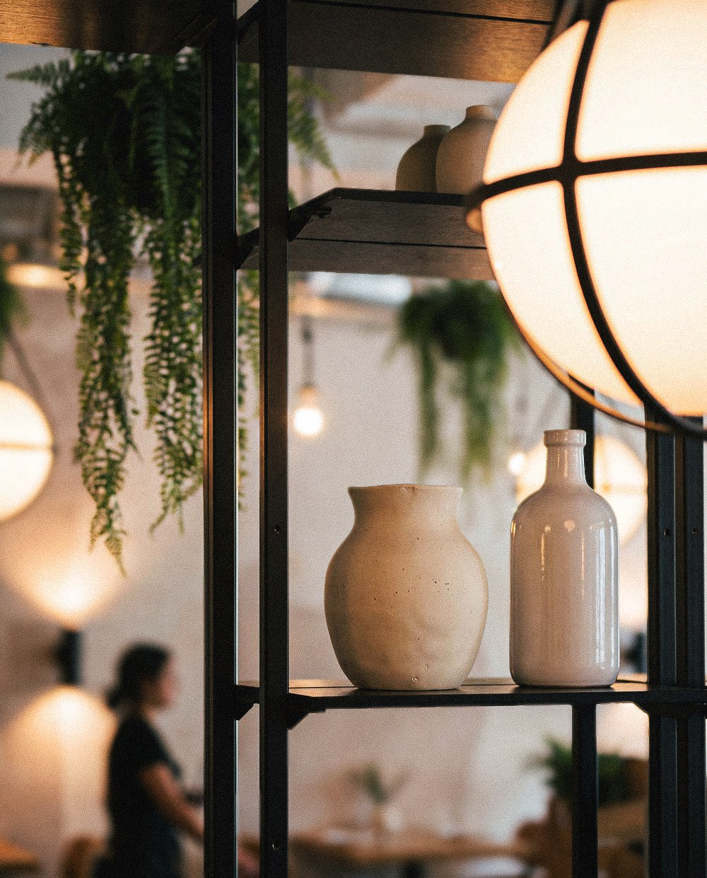 Ceramic vases and warm globe lamp on open shelving at Ventura Wynwood